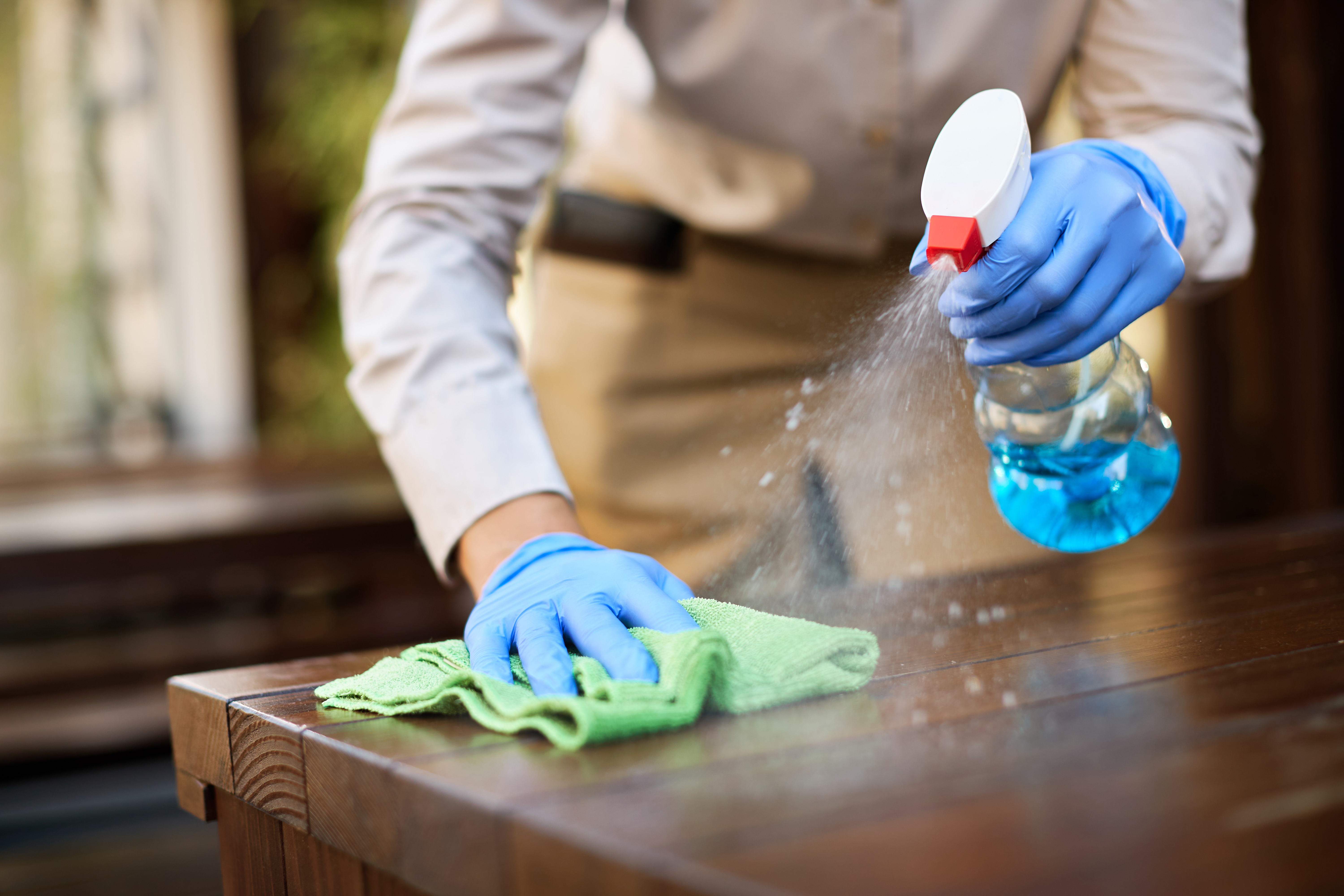 Professional cleaner disinfecting tables